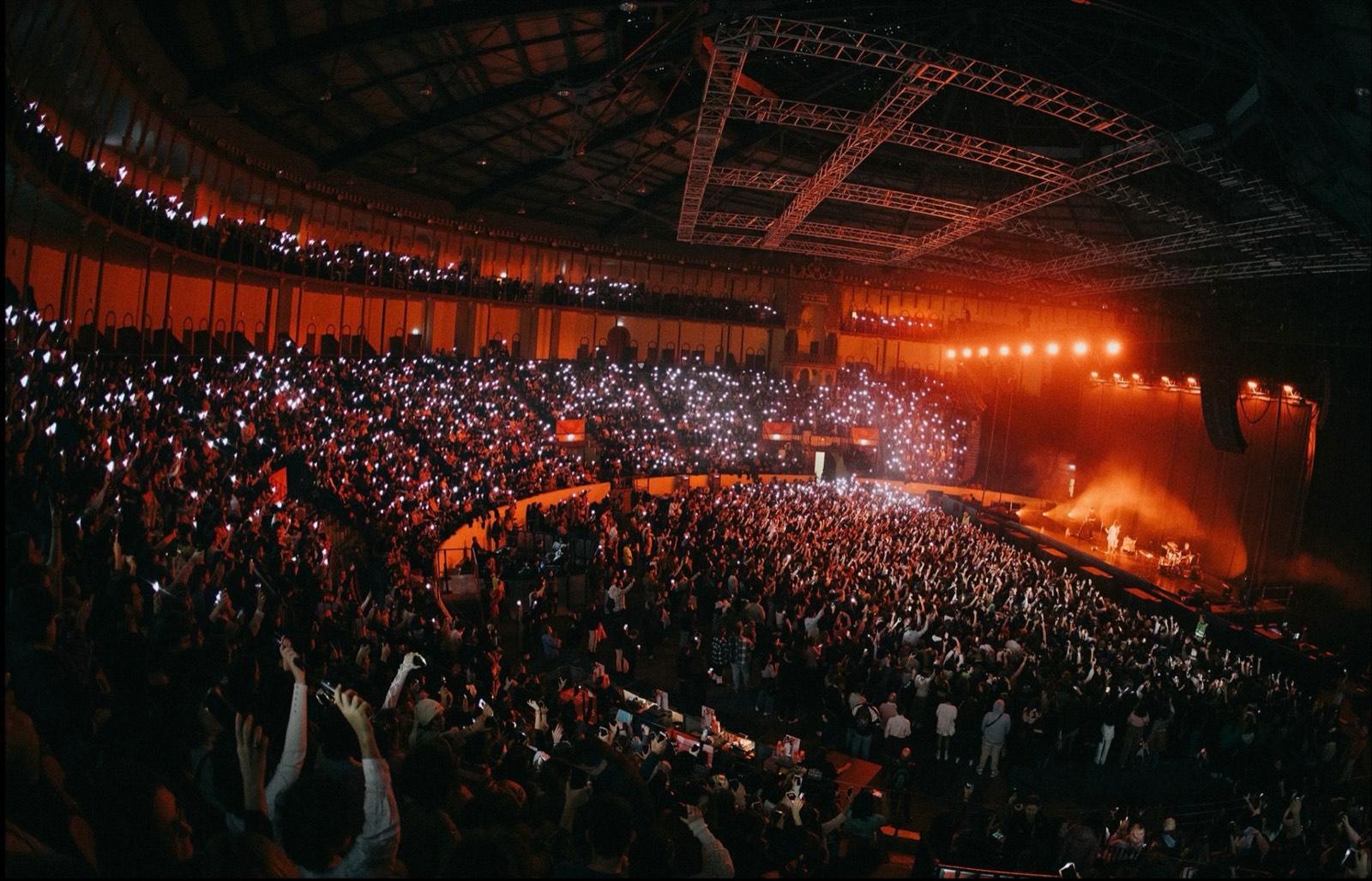 Packed arena waving phone lights during a show